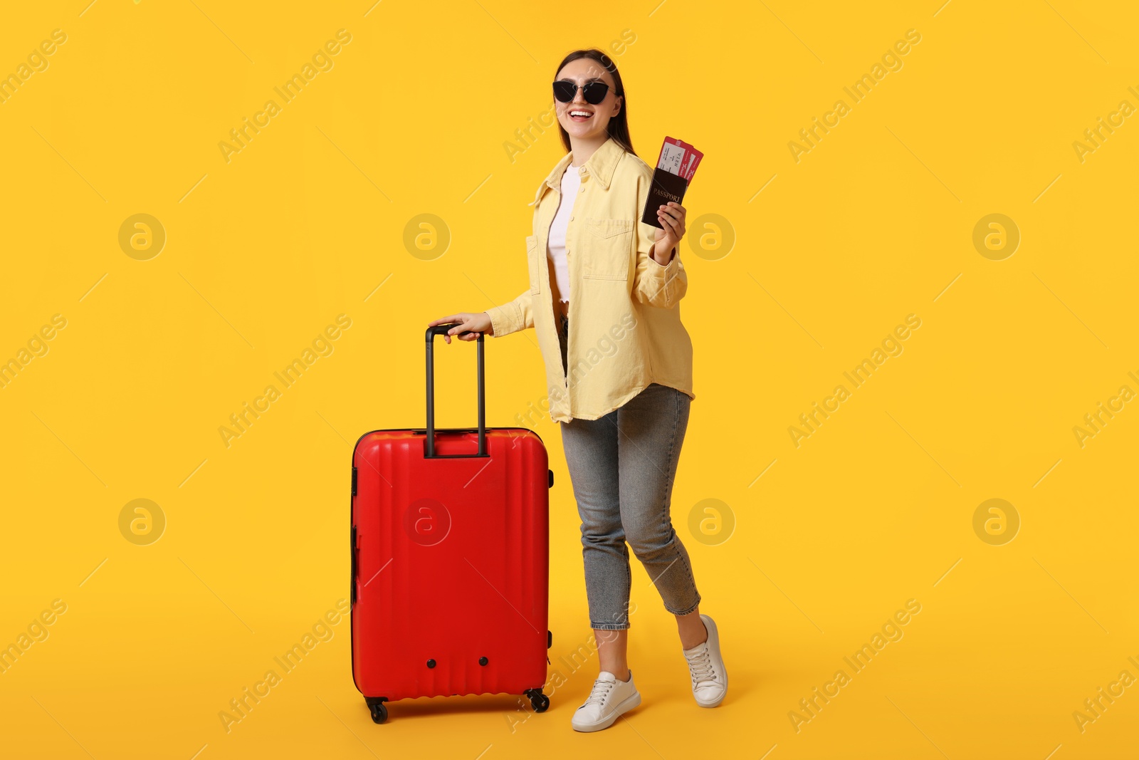 Photo of Woman with tickets, passport and suitcase on orange background