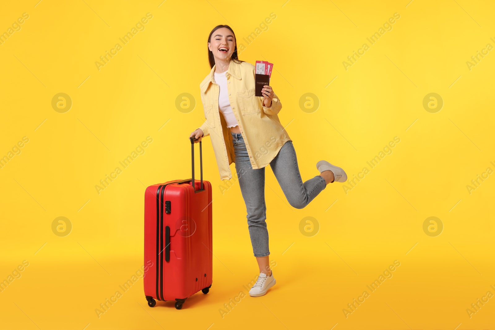 Photo of Woman with tickets, passport and suitcase on orange background