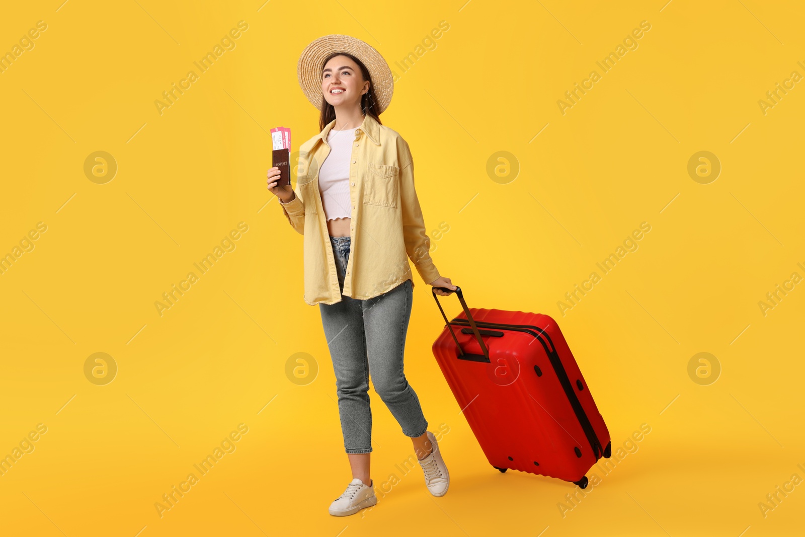 Photo of Woman with tickets, passport and suitcase on orange background