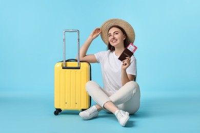 Photo of Woman with ticket, passport and suitcase on light blue background