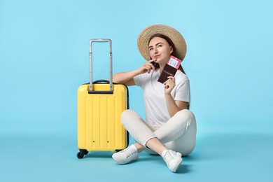 Photo of Woman with ticket, passport and suitcase on light blue background