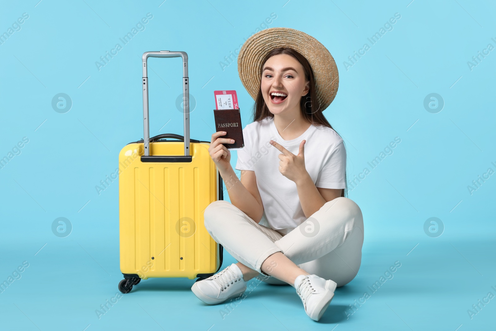 Photo of Woman with ticket, passport and suitcase on light blue background