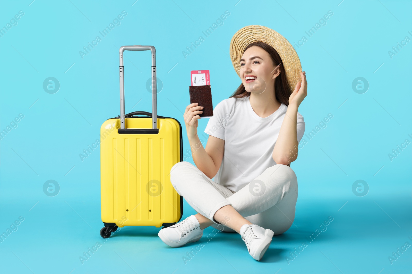 Photo of Woman with ticket, passport and suitcase on light blue background