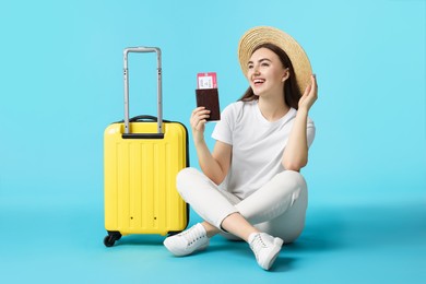 Woman with ticket, passport and suitcase on light blue background