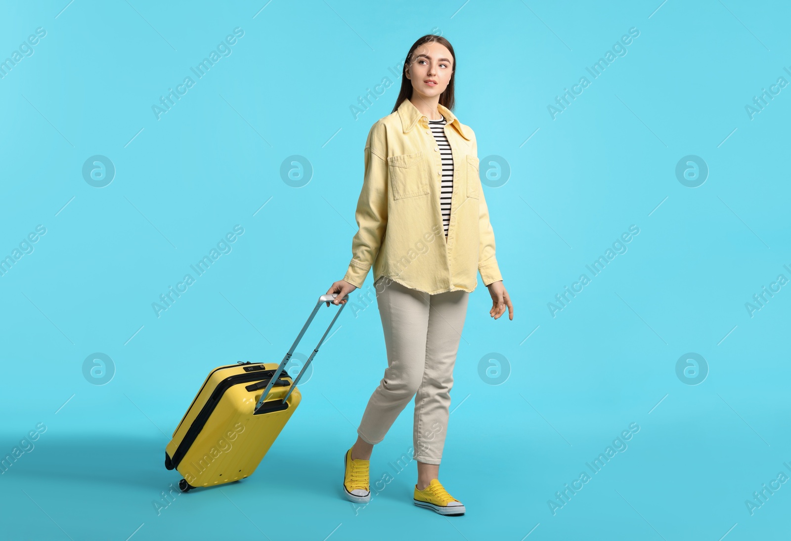 Photo of Woman with suitcase on light blue background