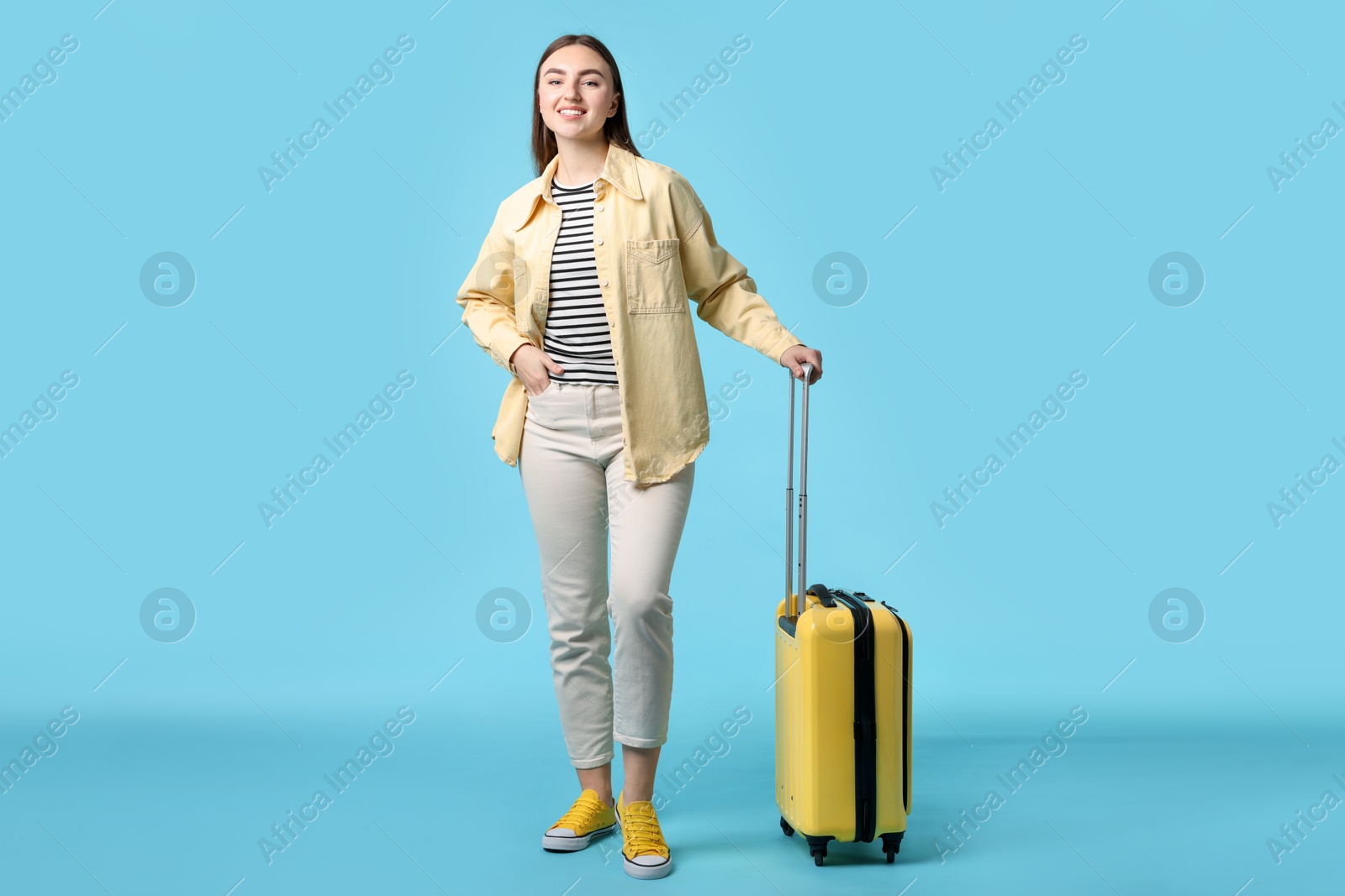 Photo of Woman with suitcase on light blue background