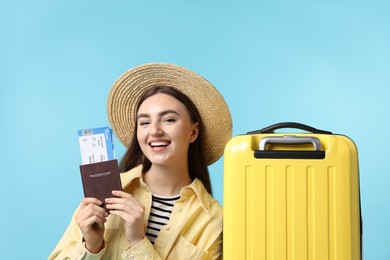 Photo of Woman with ticket, passport and suitcase on light blue background