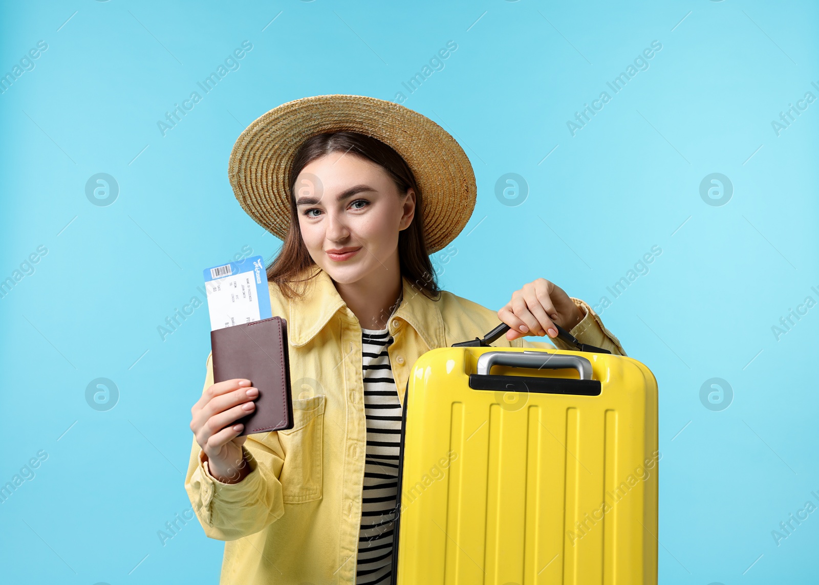 Photo of Woman with ticket, passport and suitcase on light blue background