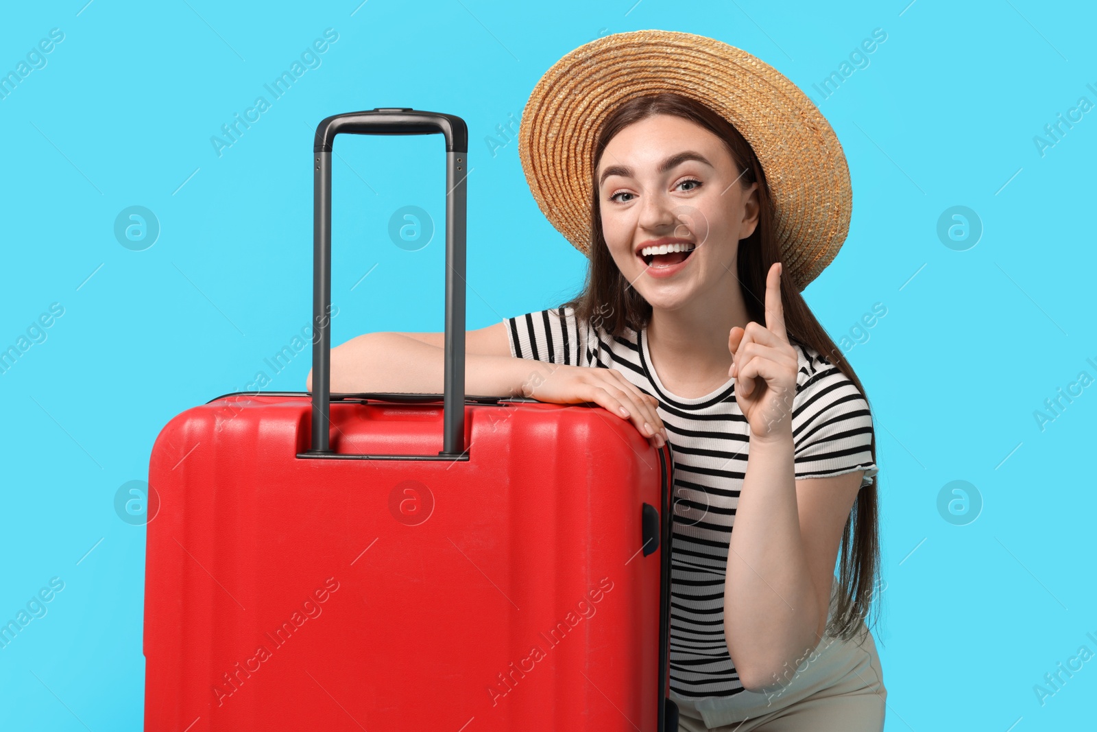 Photo of Woman in straw hat with suitcase on light blue background