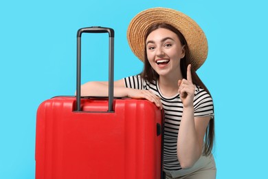 Woman in straw hat with suitcase on light blue background