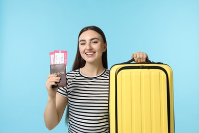 Photo of Woman with tickets, passport and suitcase on light blue background