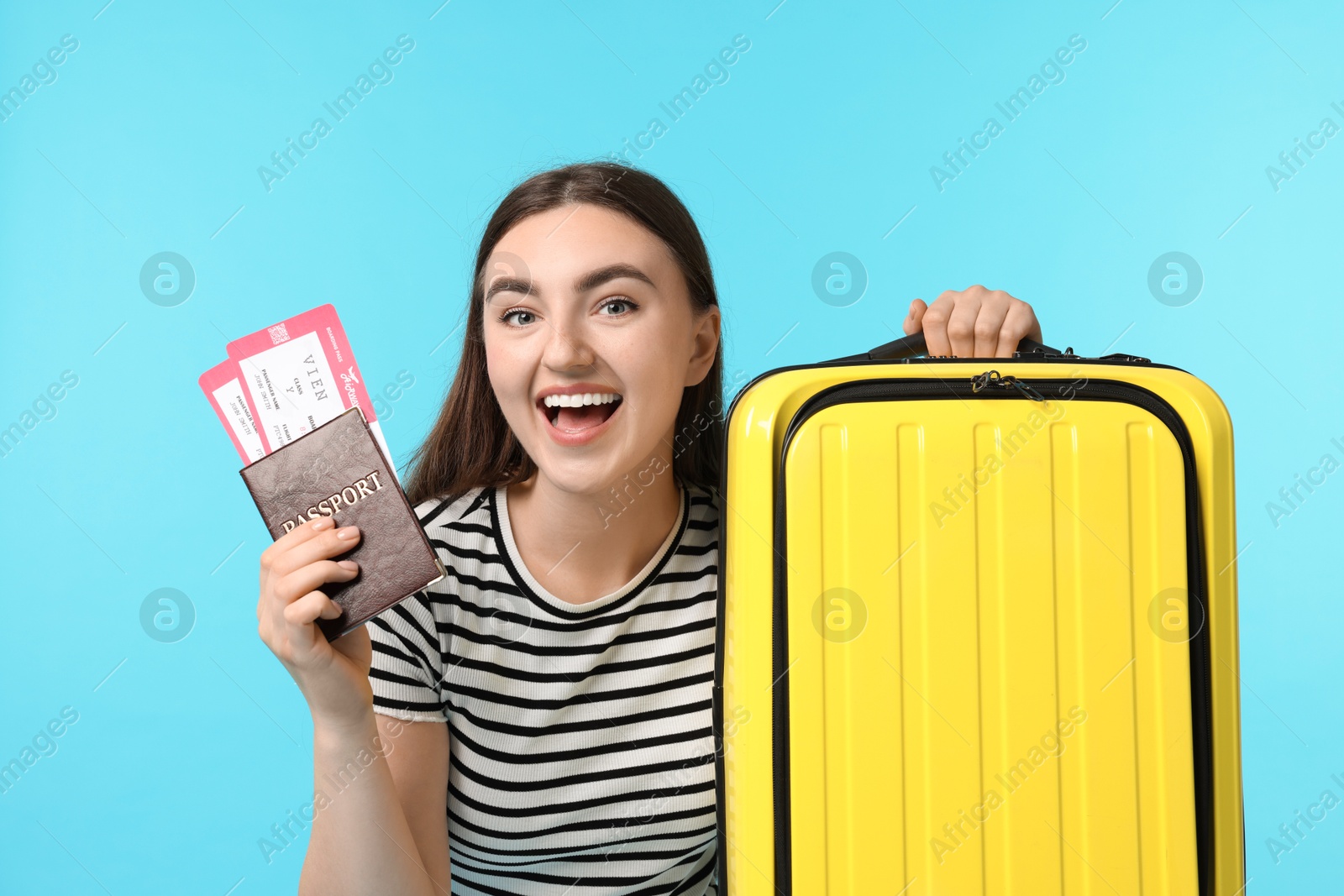 Photo of Woman with tickets, passport and suitcase on light blue background