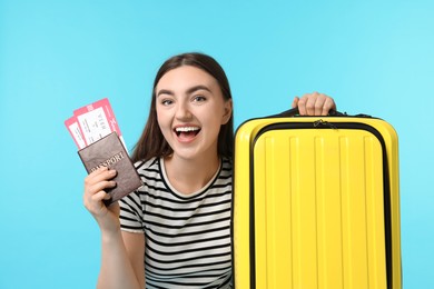 Photo of Woman with tickets, passport and suitcase on light blue background