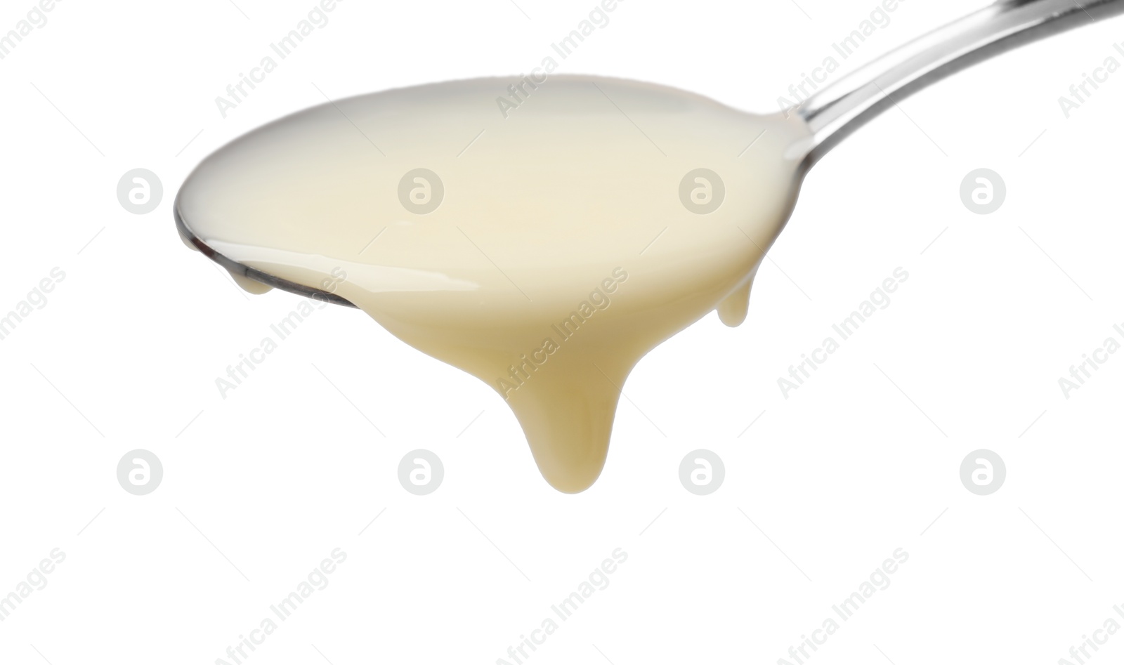 Photo of Delicious condensed milk pouring from spoon isolated on white