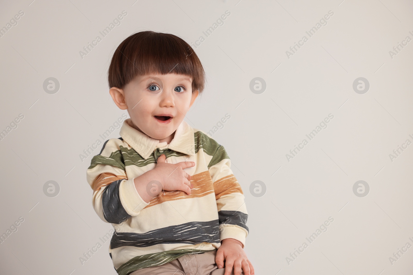 Photo of Cute little boy on light grey background. Space for text