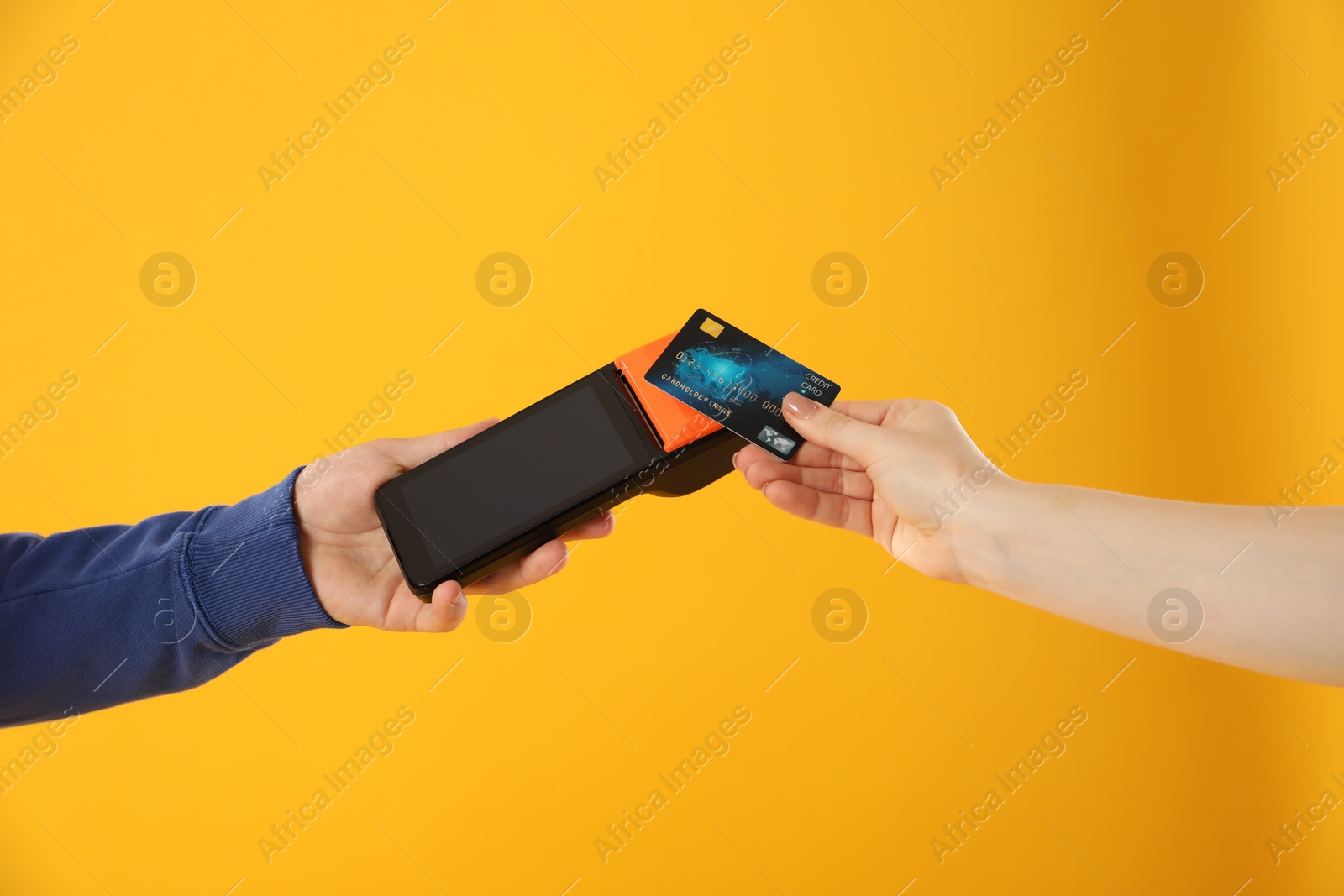 Photo of Man taking payment from client via terminal on yellow background, closeup