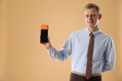 Photo of Happy young man with payment terminal on beige background, space for text