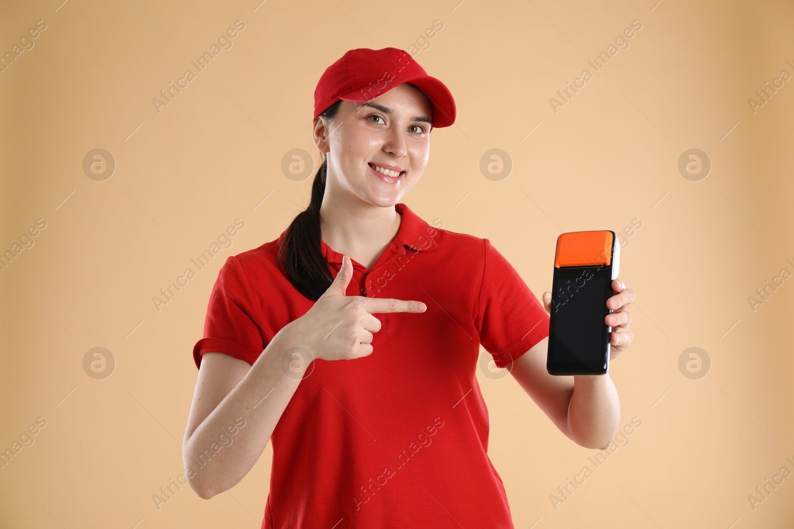 Photo of Happy courier with payment terminal on beige background