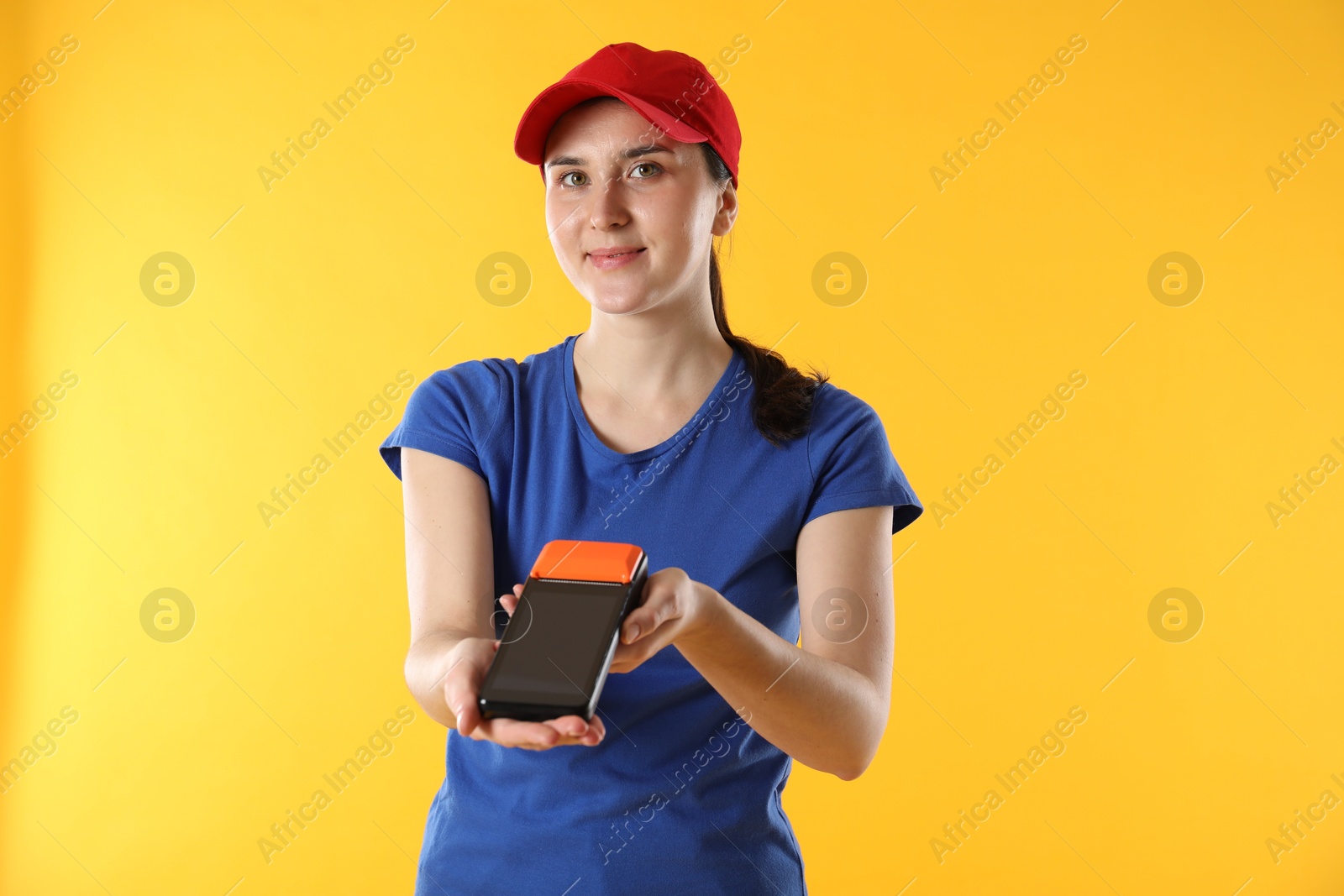 Photo of Courier with payment terminal on yellow background