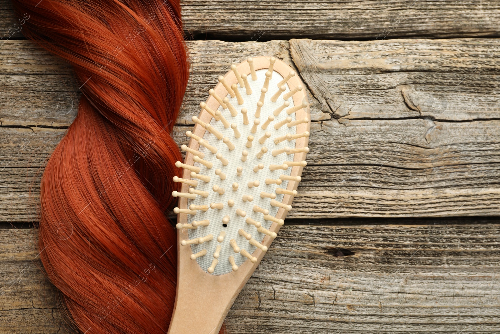 Photo of Brush and lock of hair on wooden table, top view. Space for text