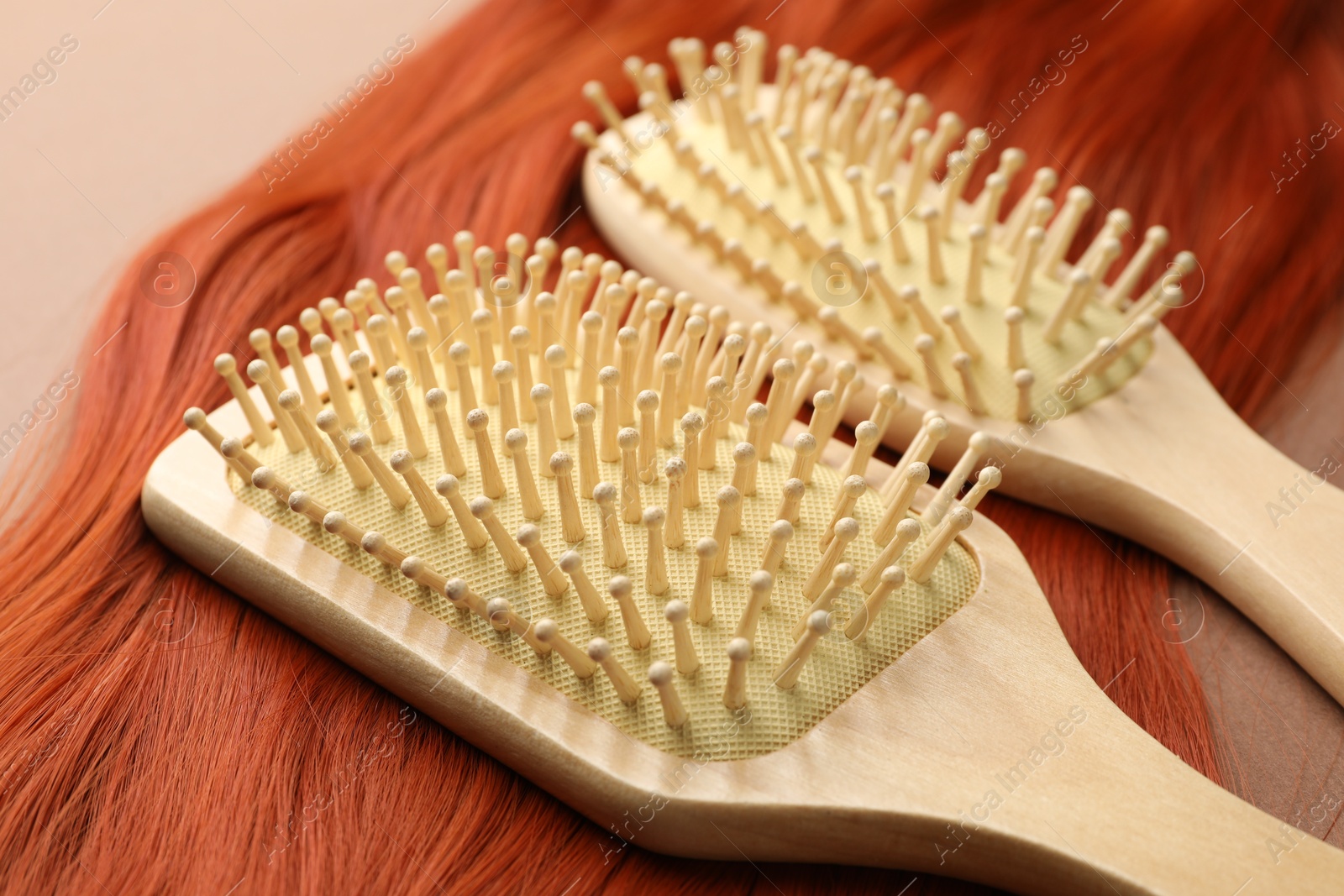 Photo of Brushes and lock of hair on brown background, closeup