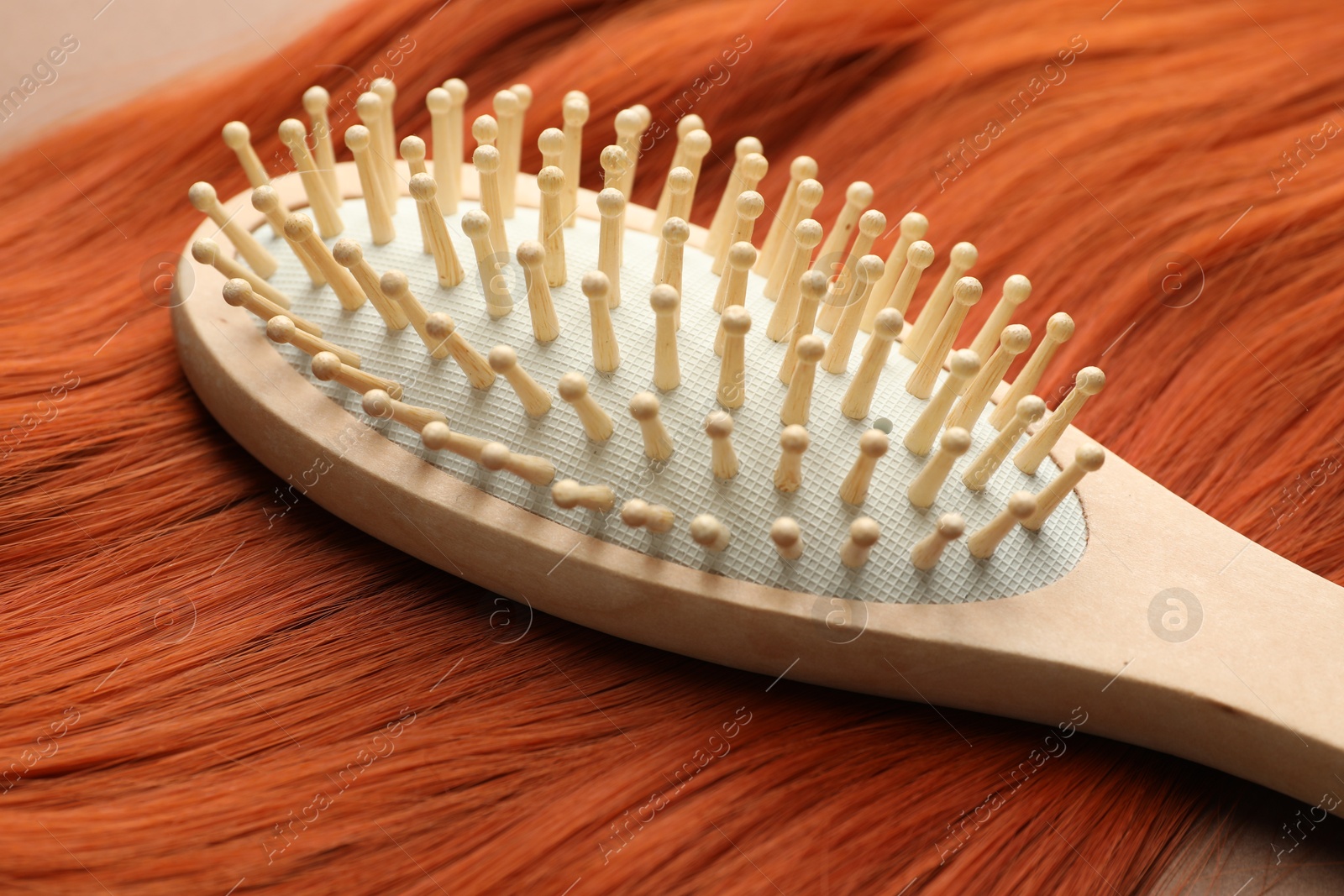 Photo of Brush and lock of hair on brown background, closeup