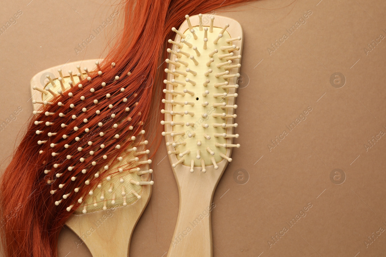 Photo of Wooden brushes and lock of hair on beige background, flat lay. Space for text