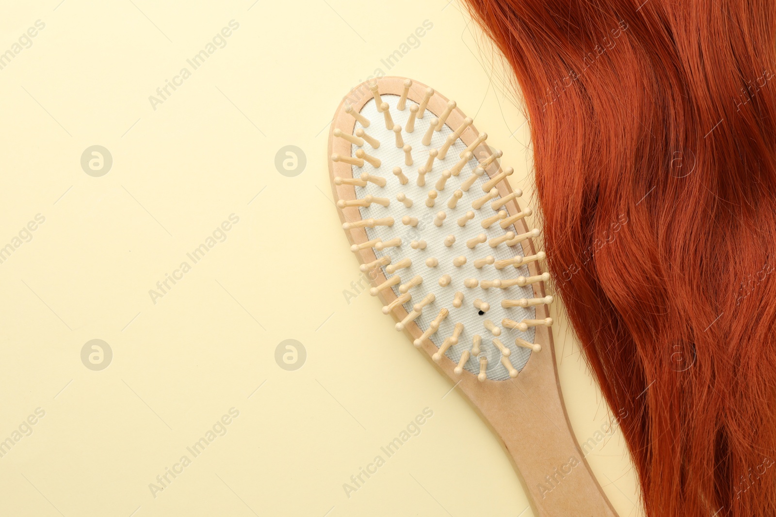 Photo of Wooden brush and lock of hair on beige background, top view. Space for text