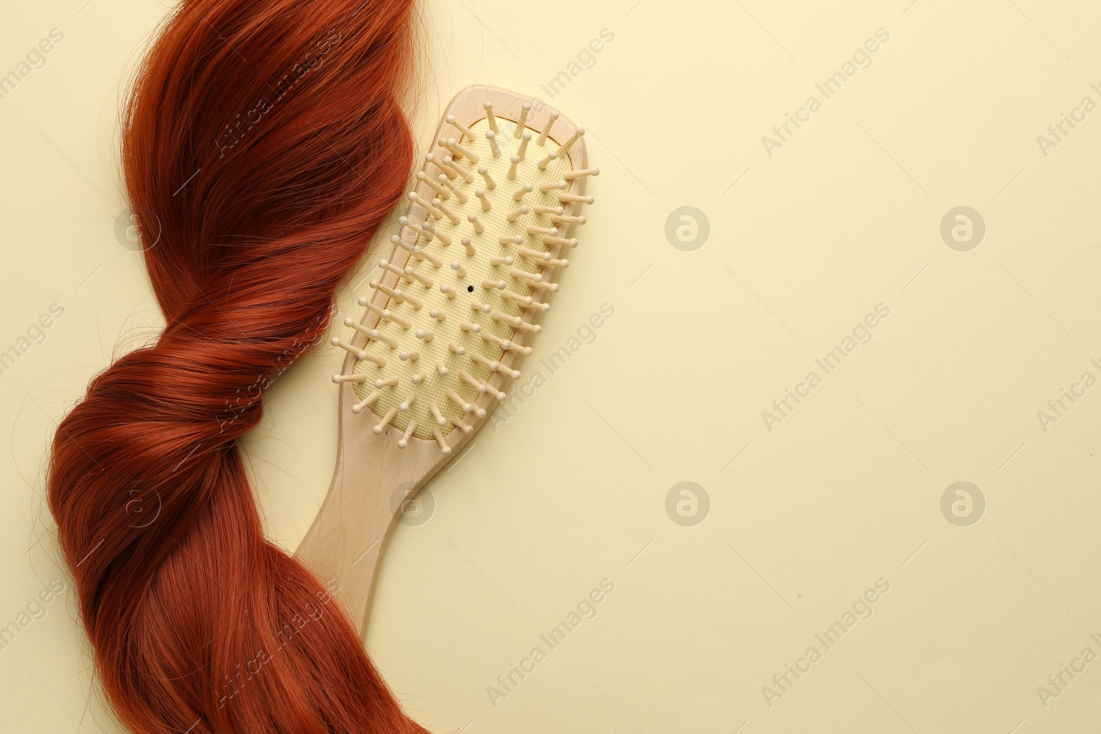 Photo of Wooden brush and lock of hair on beige background, top view. Space for text