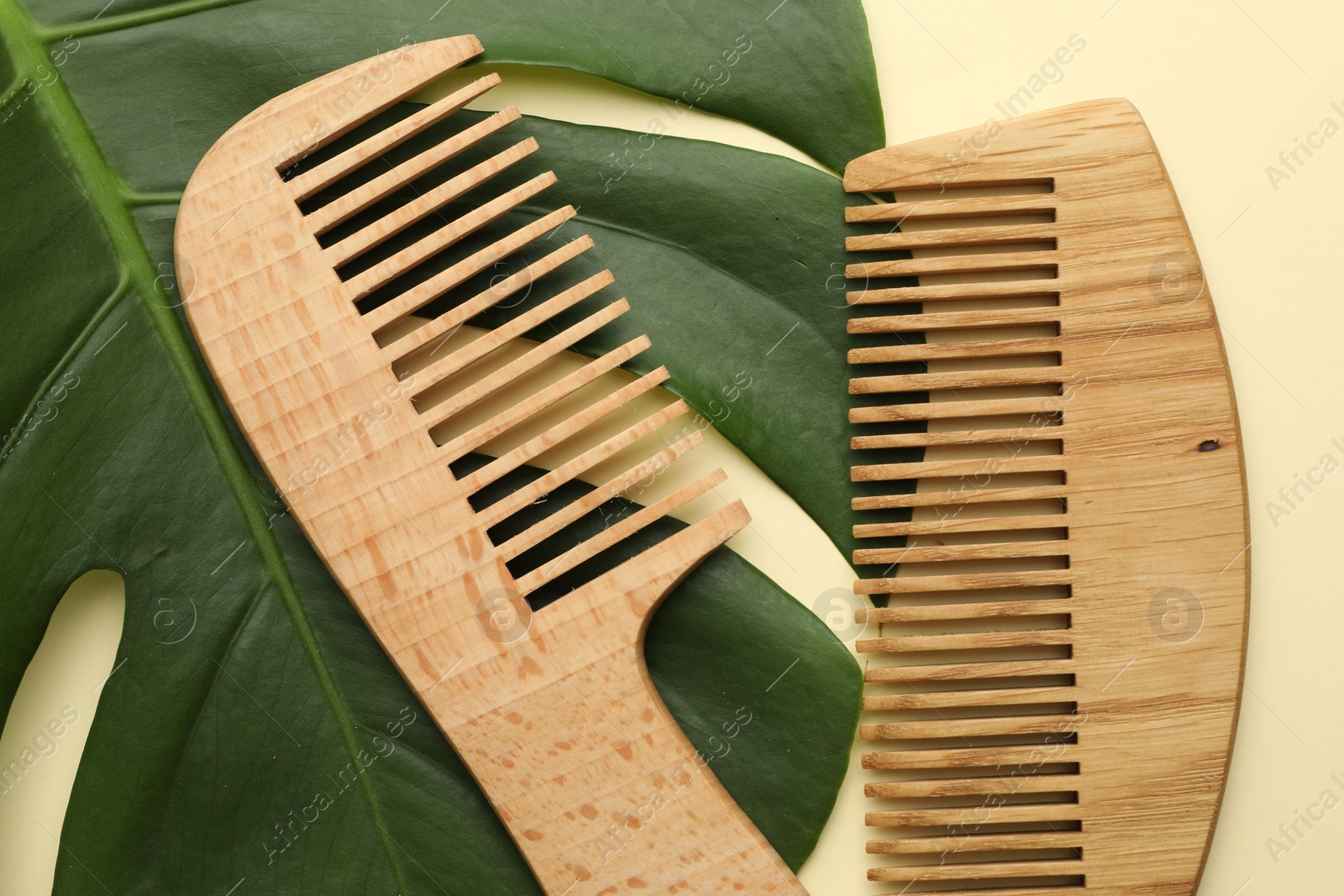 Photo of Wooden combs and monstera leaf on beige background, flat lay