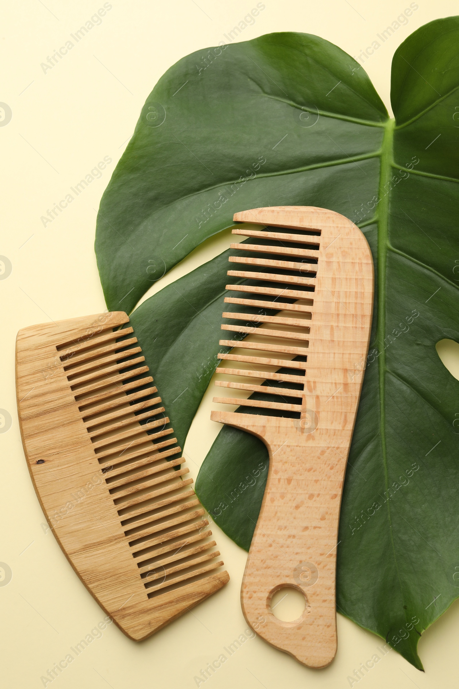 Photo of Wooden combs and monstera leaf on beige background, flat lay