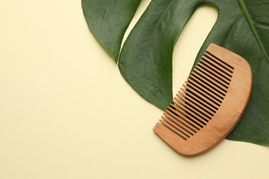 Photo of Wooden comb and monstera leaf on beige background, top view. Space for text