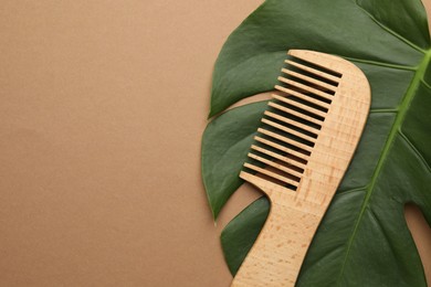 Photo of Wooden comb and monstera leaf on beige background, top view. Space for text