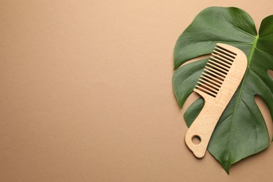 Photo of Wooden comb and monstera leaf on beige background, top view. Space for text