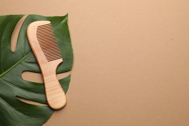 Photo of Wooden comb and monstera leaf on beige background, top view. Space for text