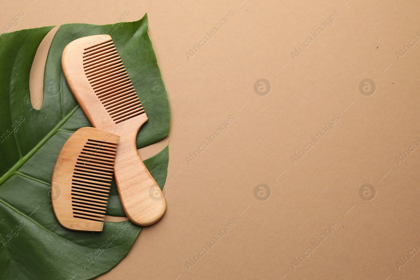 Photo of Wooden combs and monstera leaf on beige background, top view. Space for text