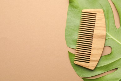 Photo of Wooden comb and monstera leaf on beige background, top view. Space for text