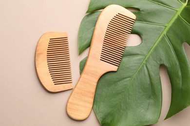 Photo of Wooden combs and monstera leaf on beige background, flat lay