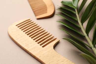 Photo of Wooden combs and branch with leaves on beige background, closeup