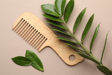 Photo of Wooden comb and branch with leaves on beige background, flat lay