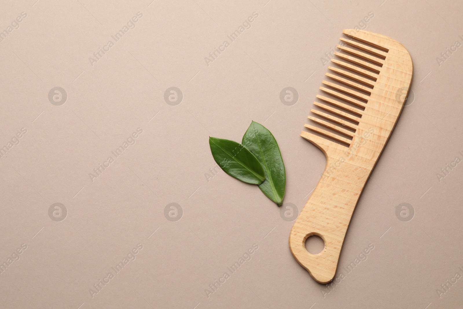 Photo of Wooden comb and leaves on beige background, flat lay. Space for text