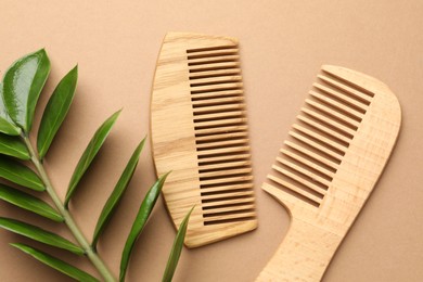 Photo of Wooden combs and branch with leaves on beige background, flat lay