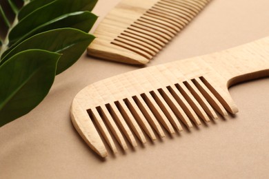 Photo of Wooden combs and branch with leaves on beige background, closeup