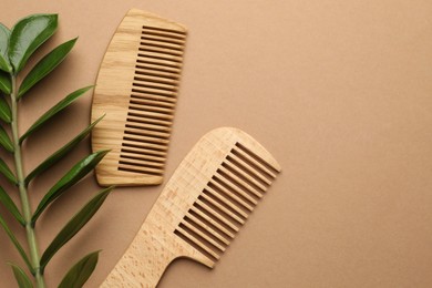 Photo of Wooden combs and branch with leaves on beige background, flat lay. Space for text