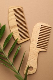 Photo of Wooden combs and branch with leaves on beige background, flat lay