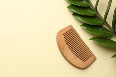 Photo of Wooden comb and branch with leaves on beige background, flat lay. Space for text