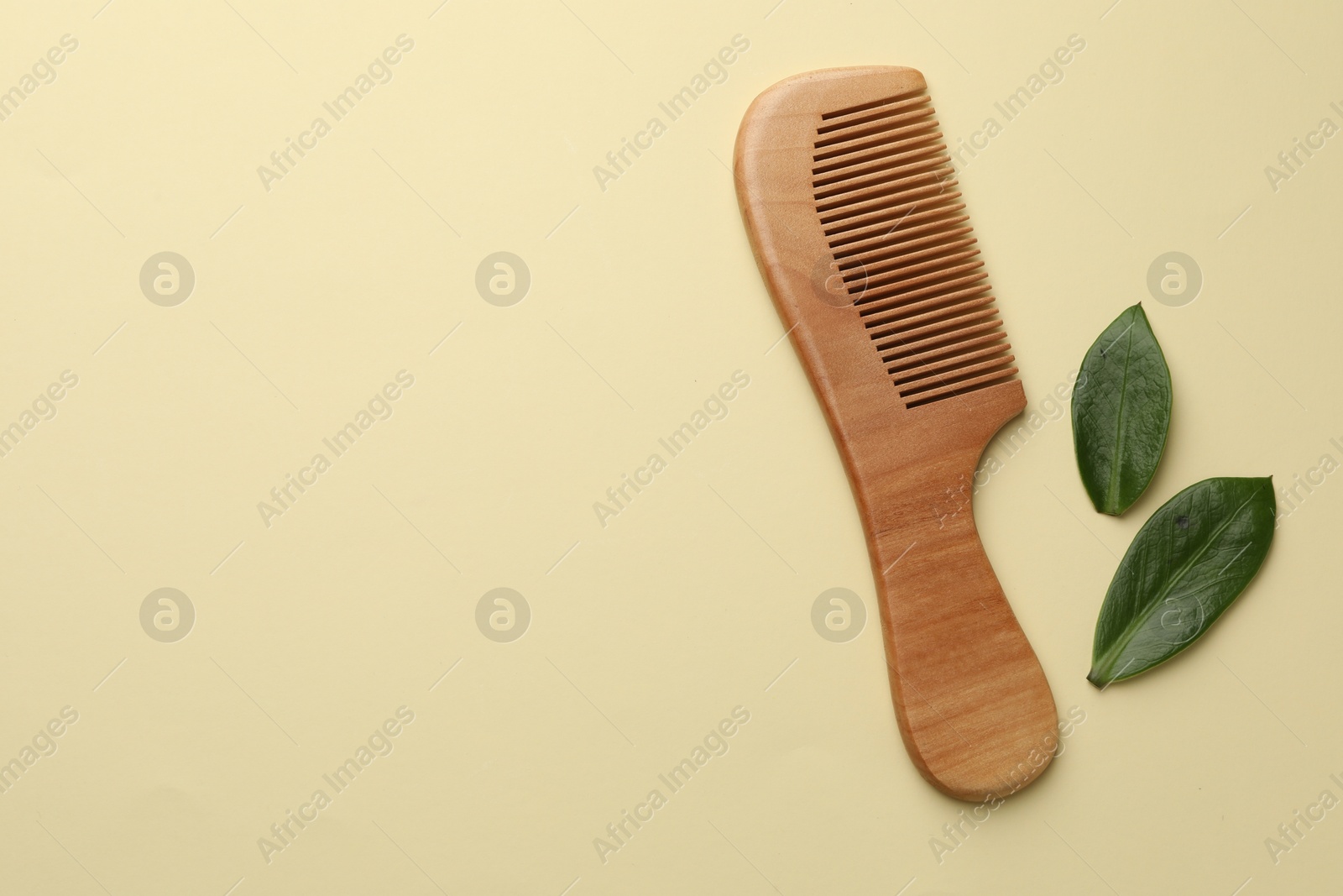 Photo of Wooden comb and leaves on beige background, flat lay. Space for text