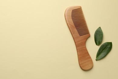 Photo of Wooden comb and leaves on beige background, flat lay. Space for text