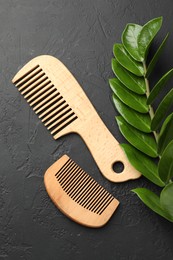 Photo of Wooden combs and branch with leaves on dark textured table, flat lay