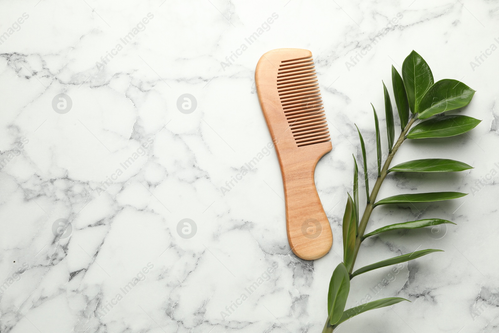 Photo of Wooden comb and branch with leaves on white marble table, flat lay. Space for text